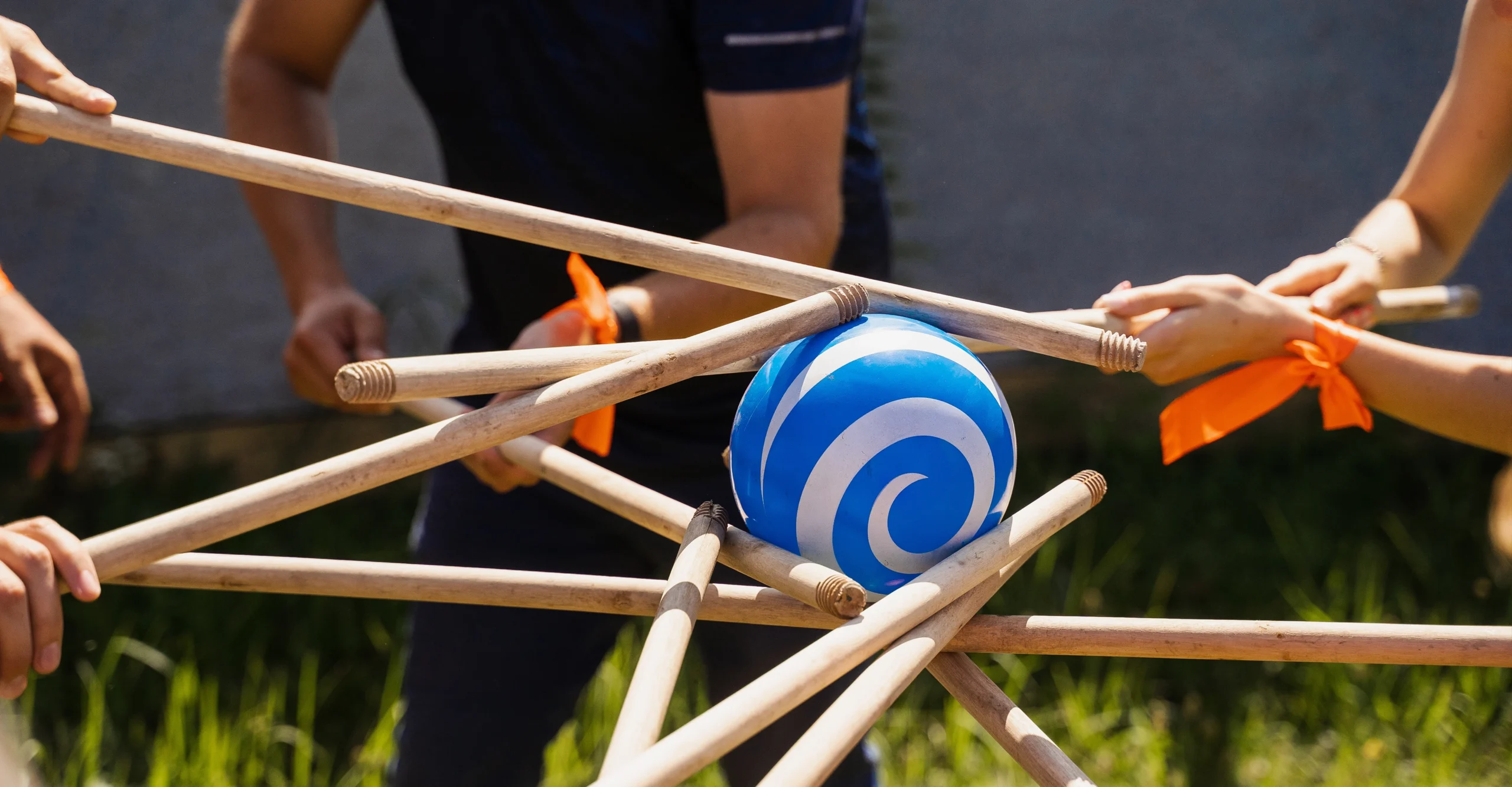 Trust Event - Folk samarbejder med træpinde for at flytte en blå og hvid bold.